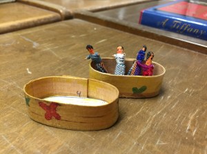 Very small dolls in a wooden pillbox.